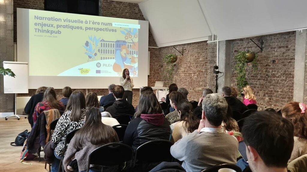 Photo of the Thinkpub Conference at the Brussels Book Fair, organized with PILEn. The speaker, Marie-Laurence de Rocher, is standing in front of the audience with a microphone in her hands. Behind is the poster of the event.